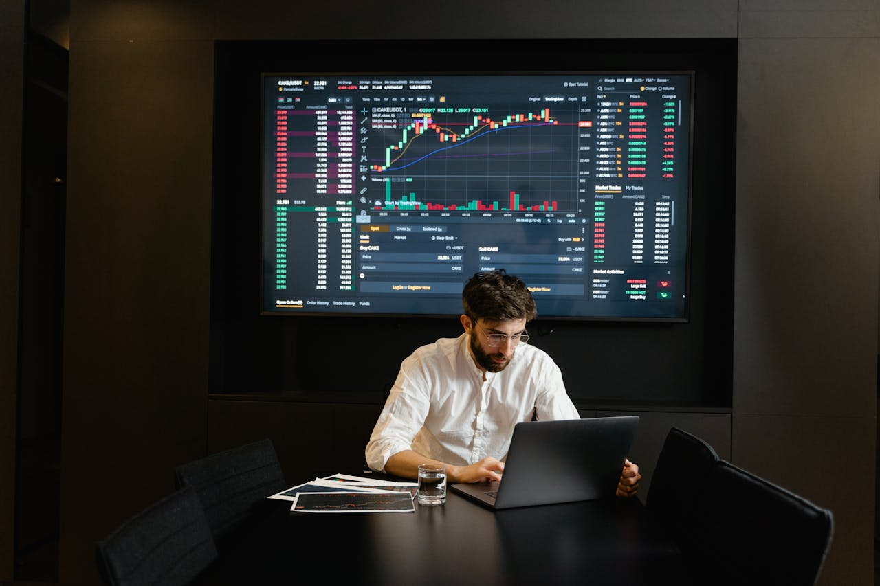 Businessman using laptop in office analyzing stock market charts. Professional finance and investment concept.